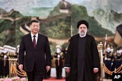 2023 年 2 月 14 日,在北京人民大会堂举行的欢迎仪式上,来访的伊朗总统易卜拉欣·莱希(Ebrahim Raisi)(右)在检阅仪仗队后与中国国家主席习近平同行。