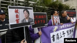 香港民主抗议者举着铜锣湾书店老板桂民海(左)和李波(右)的肖像(2016年1月19日)。