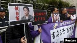 香港民主抗议者举着铜锣湾书店老板桂民海(左)和李波(右)的肖像(2016年1月19日)