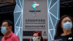 戴着口罩的路人经过一座北京冬奥会倒计时显示屏。(美联社照片)