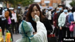 中国青岛的医护人员正在给一名妇女做核酸检测。(2020年10月13日)