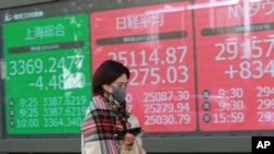 2020年11月10日星期二,一名女子走过东京一家证券公司的电子股票显示屏。