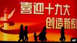 北京居民走过迎接中共十九大召开的大型电子屏幕。(2017年10月15日)