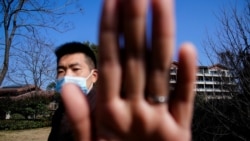 资料照片:中国安全人员阻挡新闻摄影师拍摄世界卫生组织一个专家组在武汉的行踪。(2021年2月6日)