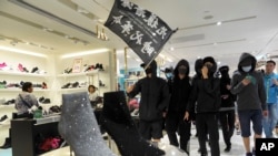 香港黑衣抗议者在铜锣湾的一个商场里举“光复香港,时代革命”的旗子示威。(2019年12月26日)