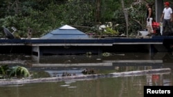 在波多黎各的瓜亚塔卡水坝附近,洪水淹没房屋,人们站在房顶上(2017年9月23日)