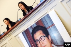 中国维权律师郭飞雄的妻子张青(左)和女儿杨天娇在参加美国国会听证会前举行记者会,讲台前有郭飞雄的照片(2013年10月29日)
