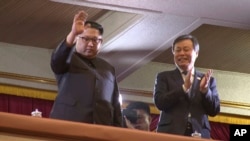 朝鲜领导人金正恩(左)向在平壤演出的一个韩国艺术团招手致意,率团的韩国文化体育观光部长官都钟焕在一旁鼓掌。 (2018年4月1日)