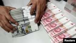 资料照:中国山西省太原市一家银行的职员正在点数人民币和美元。