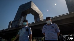 资料照:两名警察在北京街头巡逻,背景是中国中央电视台大楼。(2020年5月19日)