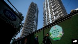 资料照:行人走过北京一处豪华住宅工地旁。(2024年9月24日)