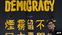 一位香港民主抗议者站在一条横幅前。(2014年9月30日)