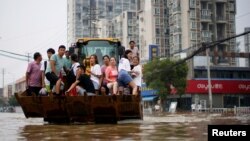 河南郑州暴雨后居民乘斗车疏散。(2021年7月23日)