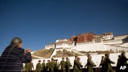 在西藏拉萨的布达拉宫前面,军人行进,有妇女祈祷(2007年2月22日)