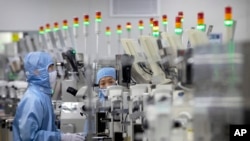 资料照片:2020年5月14日,佩戴保护设备的员工在北京记者的政府组织游览期间在瑞萨电子的半导体生产设施中工作。 中国已宣布退税,以便在美国制裁后促进其半导体产业的增长,这些制裁削减了对科技巨头华为和其他一些公司的美国处理器筹码。