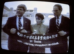 资料照:电视画面显示,来自加州的民主党众议员南希·佩洛西(中)、来自乔治亚州的民主党众议员本·琼斯(左)和来自华盛顿州的共和党众议员约翰·米勒在天安门广场展示横幅,向为中国民主事业牺牲的烈士致敬。(1991年9月4日)