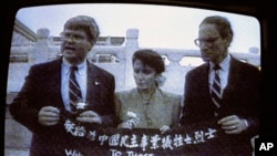 资料照:电视画面显示,来自加州的民主党众议员南希·佩洛西(中)、来自乔治亚州的民主党众议员本·琼斯(左)和来自华盛顿州的共和党众议员约翰·米勒在天安门广场展示横幅,向为中国民主事业牺牲的烈士致敬。(1991年9月4日)