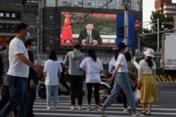 北京街头的行人观看电子屏幕上中国国家主席习近平通过视频在世卫大会视频开幕式上致辞。(2020年5月18日)