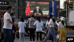 北京街头的行人观看电子屏幕上中国国家主席习近平通过视频在世卫大会视频开幕式上致辞。(2020年5月18日)
