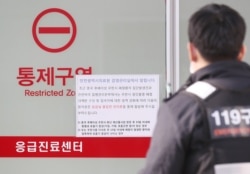 一名韩国救护人员走过医院墙上张贴的警示武汉肺炎的通知,这所医院收治了一名来自武汉感染了新型冠状病毒的中国妇女。(2020年1月20日)