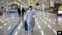 身穿防护服的朝鲜工作人员在平壤国际机场喷洒消毒水并检测旅客的体温。(2020年2月1日)