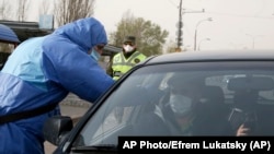 Фото для ілюстрації: поліцейський в захисному костюмі перевіряє температуру водія поблизу Києва, 16 квітня 2020 року