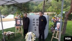 2019年10月18日,赵紫阳夫妇墓碑前摆放着出席骨灰安葬仪式的亲友们献的鲜花。赵紫阳之子赵二军(右)立于碑前。(美国之音艾伦拍摄)
