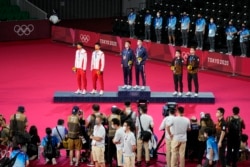 东京奥运会羽毛球男双颁奖台上,台湾选手李洋及王齐麟获金牌,中国选手李俊慧与刘雨辰获银牌,马来西亚选手获铜牌。(2021年7月31日)