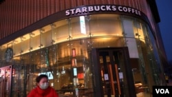 一名戴口罩的女士路过星巴克在北京的一家门店。(2020年2月20日)