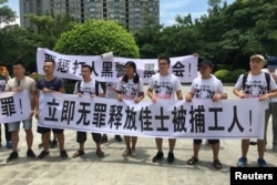 2018年8月6日,人们在中国广东省深圳市坪山区燕子岭派出所外示威,手持标语,支持佳士工厂工人。