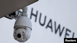 资料照:在北京一家商场外的华为标志旁安装了一个监控摄像头。(2019年1月29日)