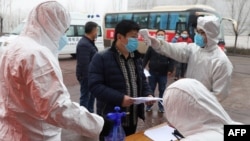 山东省邹平在公交车站设立检查点为来自河南的农民工测量体温。(2020年2月25日)