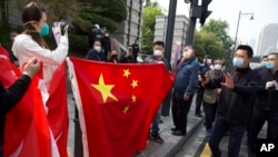 武汉保安试图驱散在一个公园外举着国旗和花束祭奠新冠疫情死难者的人群。(2020年4月4日)