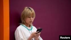 一名中国女子在街上使用苹果手机。(路透社2023年9月27日)