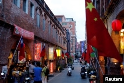台湾金门一条街道商店旁插有中国和台湾的旗帜。(2018年8月19日)