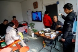 在北京打工的杨念连(音)和他租住的京郊马驹桥小区的房东一家人一起过年。(2021年2月11日)