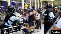 8月13日,防暴警察使用胡椒水驱散反送中大游行的抗议者。在此之前,一名女性抗议者在香港国际机场的集会中眼部受伤。