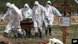 俄罗斯圣彼得堡的丧葬业人员身穿防护服掩埋新冠病毒死者,死者的亲友远远地遥望他们的亲人在新冠患者死去后被指定的区域下葬。(2020年5月15日)