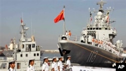 中国海军官兵登上青岛号导弹驱逐舰(右)去参加2013年9月中美海军联合演习。