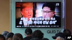 People watch a TV screen showing images of U.S. President Donald Trump, left, and North Korean leader Kim Jong Un during a news program at the Seoul Railway Station in Seoul, South Korea, May 25, 2018.