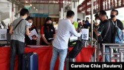马来西亚和新加坡之间重新通航后,两国机场为注射过疫苗的旅客开通特别通道。图为旅客登上开往马拉西亚的大巴。