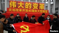 在北京举行的中国改革开放40周年纪念展上人们展开一面中共党旗。(2018年11月14日)