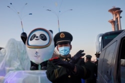 一名中国武警士兵在北京的冬奥会吉祥物前给拍照者做手势。(2022年1月15日)