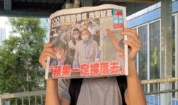 市民在天水围西铁站外领取8月11日的免费苹果日报,高举头版以示支持。 (美国之音汤惠芸)