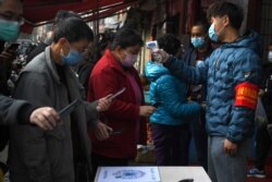 云南昆明民众戴着口罩拿着手机进行个人健康扫码方能进入超市购物。(2020年2月24日)