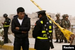 在中国新疆维吾尔自治区喀什的一条街上,警察检查一名男子的身份证,旁边有安全人员(2017年3月24日)