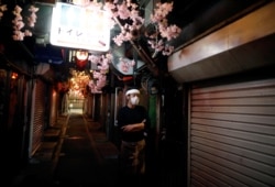 日本政府宣布紧急状态后,东京新宿区一家餐馆的服务生站在空荡无人的小巷里。(2020年4月8日)