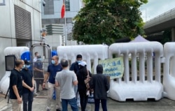中联办后门被两米高的水马围封,保安严密,家属请愿期间,中联办没有派人接收家属要求转交到深圳盐田看守所的月饼,家属只能将月饼放在中联办外 (美国之音/汤惠芸)