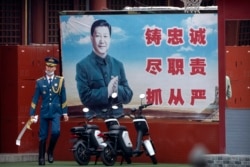 资料照片:在北京紫禁城入口附近,一名仪仗兵走过巨幅习近平宣传标语牌。(2021年9月18日)