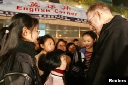 资料照片: 2005年3月25日,上海,年轻的中国学生在露天英语角与外国人练习英语。